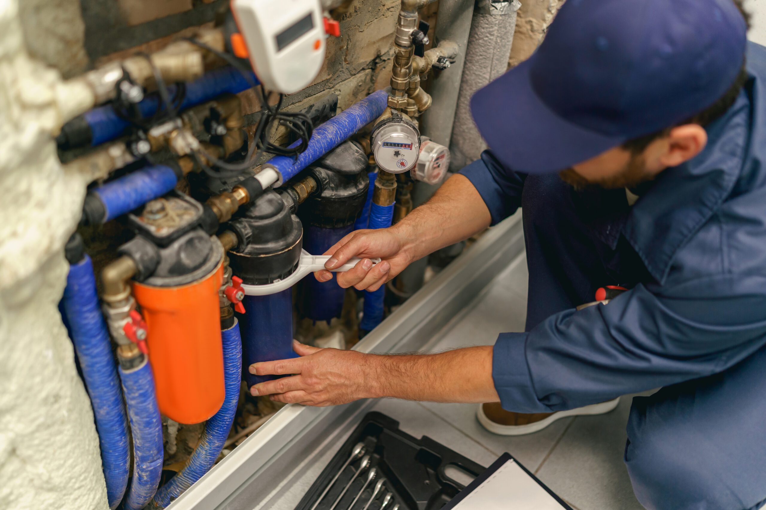 Handyman in uniform repairing water supply system at home uses a special tools