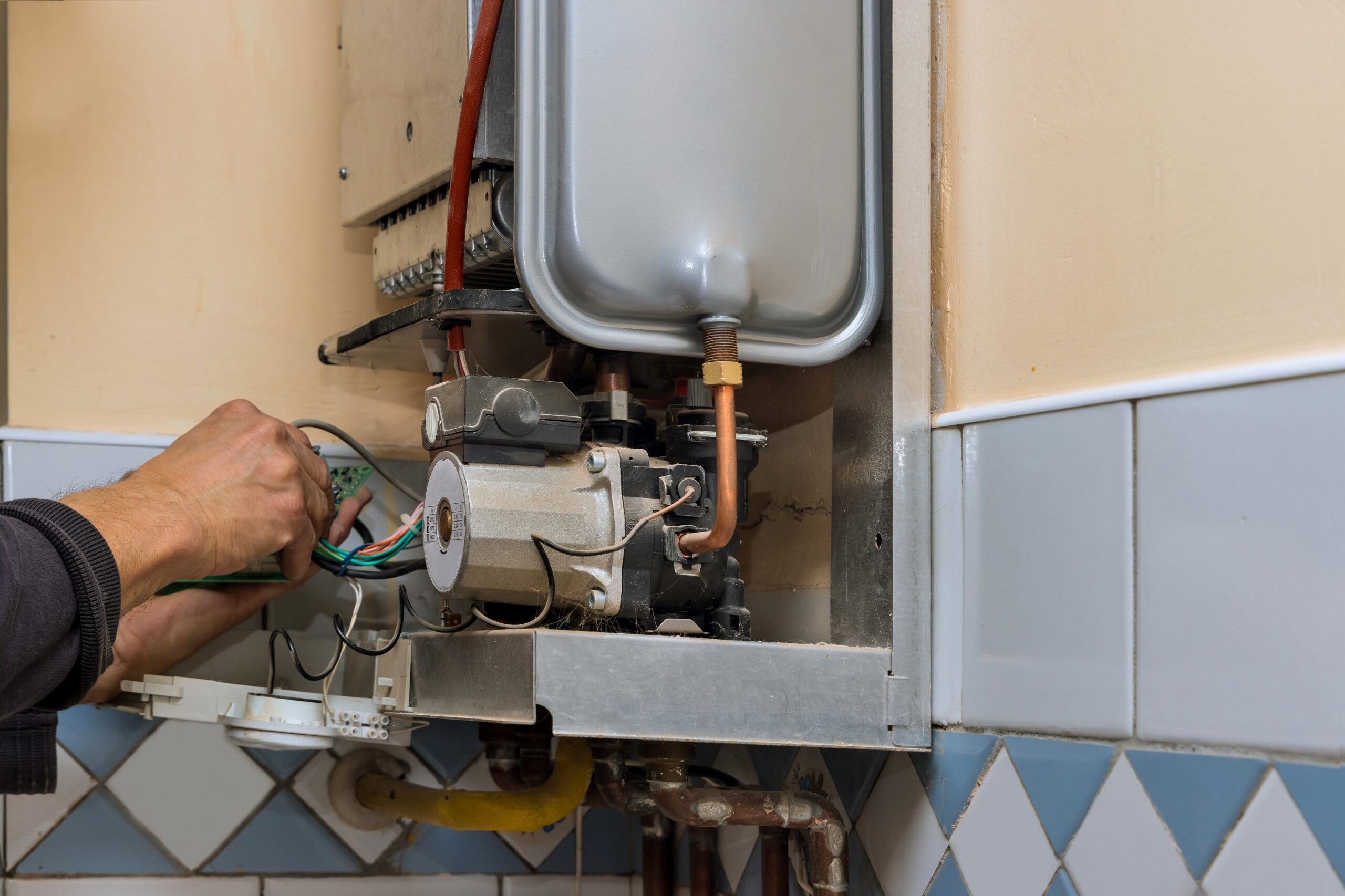 Water heater maintenance service technician repairing gas water heater indoors